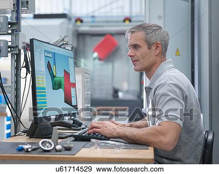 Stock Photo - Engineer watching CNC lathe progress on screen in orthopaedic factory. Fotosearch