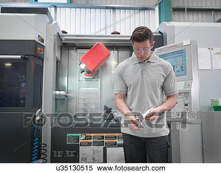 Stock Photography - Engineer with CNC lathe making artificial hip joints in orthopaedic factory. Fotosearch