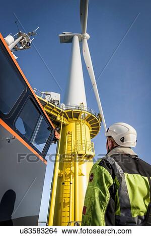Engineers climbing wind turbine from boat at offshore windfarm, low angle view View Large Photo Image Picture - Engineers climbing wind turbine from boat at offshore windfarm, low angle view. Fotosearch