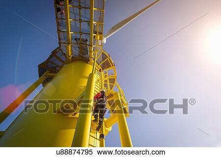Engineers climbing wind turbine from boat at offshore windfarm, low angle view View Large Photo Image Stock Photography - Engineers climbing wind turbine from boat at offshore windfarm, low angle view. Fotosearch