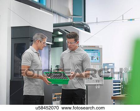 Stock Image - Engineers discussing machined products in orthopaedic factory. Fotosearch