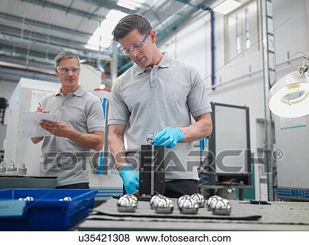 Stock Photo - Engineers finishing artificial hip joints in orthopaedic factory. Fotosearch