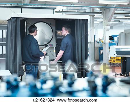 Picture - Engineers inspecting part on shadow graph machine in engineering factory. Fotosearch