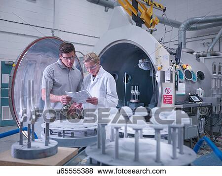 Stock Photo - Engineers with ceramic coating machine, coating artificial hip joints in orthopaedic factory. Fotosearch