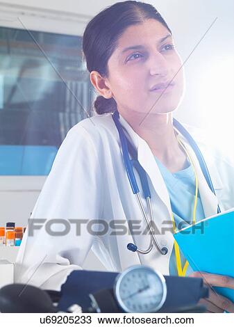 Female doctor contemplating medical notes in hospital View Large Photo Image Stock Image - Female doctor contemplating medical notes in hospital. Fotosearch