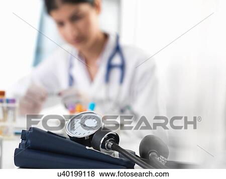 Stock Photo - Female doctor examining test tube sample at desk in clinic. Fotosearch