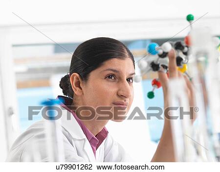 Stock Image - Female scientist in laboratory, viewing molecular model of a chemical formula. Fotosearch