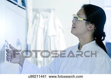 Stock Image - Female scientist opening sample cupboard in laboratory. Fotosearch