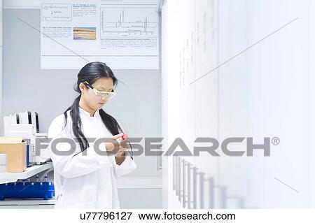 Stock Photo - Female scientist reading specimen label in laboratory. Fotosearch