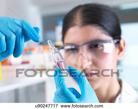 Stock Photo - Female scientist trialing medical drug ampule in laboratory. Fotosearch