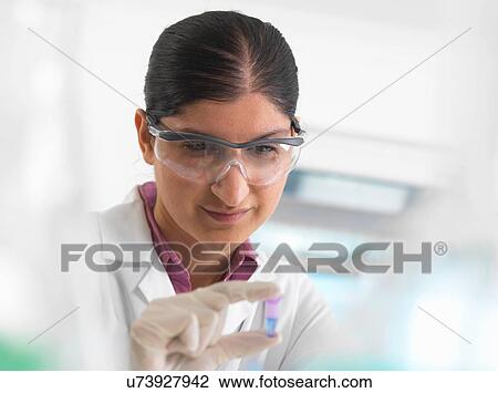 Stock Image - Female scientist viewing sample in eppendorf ahead of DNA testing in a laboratory.. Fotosearch
