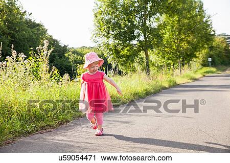 Female toddler watching her shadow toddling along rural road View Large Photo Image Stock Image - Female toddler watching her shadow toddling along rural road. Fotosearch