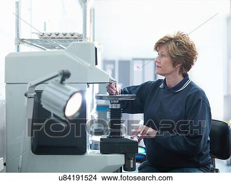 Picture - Female worker inspecting parts in engineering factory. Fotosearch