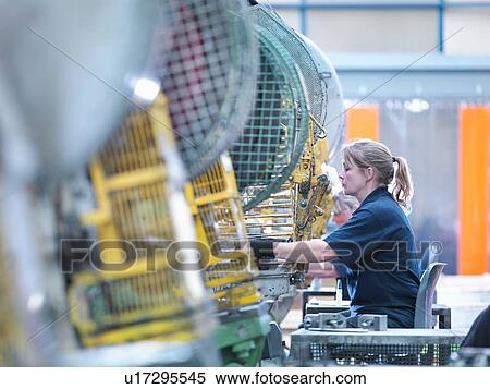 Stock Photography - Female worker operating punch machine in engineering factory. Fotosearch