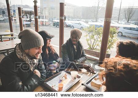 Stock Image - Five young adult friends chatting at sidewalk cafe. Fotosearch