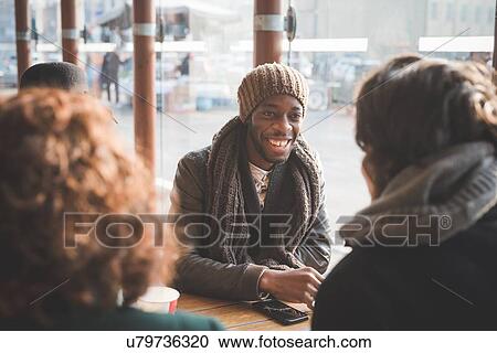 Four young adult friends chatting at sidewalk cafe View Large Photo Image Stock Image - Four young adult friends chatting at sidewalk cafe. Fotosearch