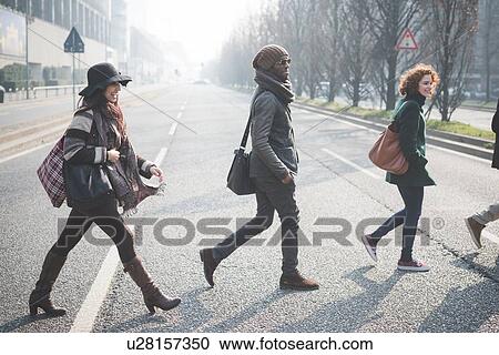 Stock Image - Four young adults crossing city road. Fotosearch