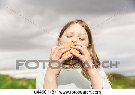 Stock Photo - Girl eating a burger, Thingvellir, Iceland. Fotosearch
