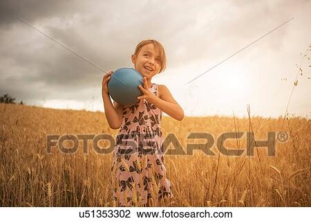 Girl holding blue ball in wheat field View Large Photo Image Stock Image - Girl holding blue ball in wheat field. Fotosearch