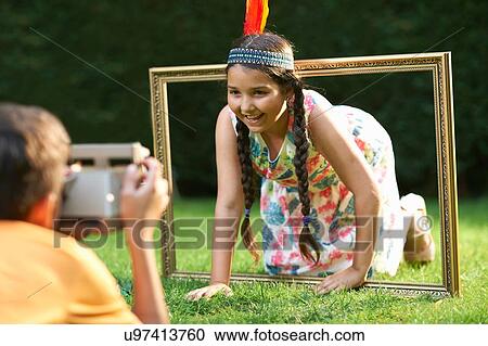 Girl kneeling, looking through picture frame, having photograph taken View Large Photo Image Stock Image - Girl kneeling, looking through picture frame, having photograph taken. Fotosearch