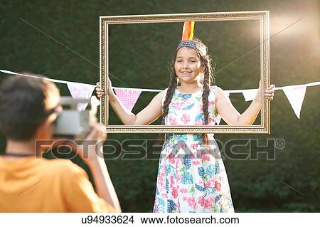 Girl looking through picture frame, having photograph taken View Large Photo Image Picture - Girl looking through picture frame, having photograph taken. Fotosearch