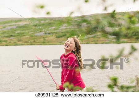 Stock Photography - Girl with fishing net laughing at lakeside, Thingvellir, Iceland. Fotosearch