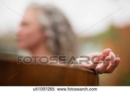 Stock Photography - Hand of mature woman meditating in hot tub at eco retreat. Fotosearch