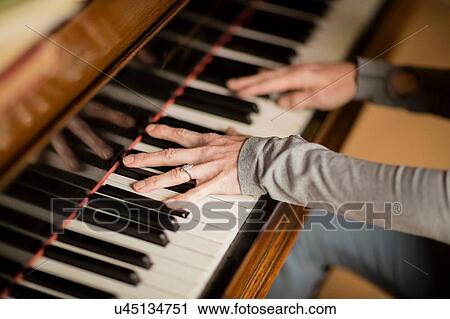 Stock Image - Hands of mature woman playing piano. Fotosearch