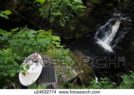 High angle view of mature woman in bubble bath in front of waterfall at eco retreat View Large Photo Image Picture - High angle view of mature woman in bubble bath in front of waterfall at eco retreat. Fotosearch
