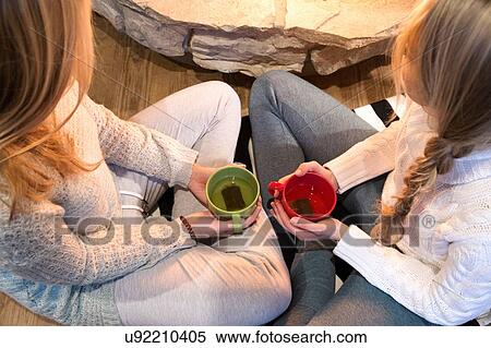 High angle view of two young women drinking herbal tea in front of fireplace View Large Photo Image Stock Photography - High angle view of two young women drinking herbal tea in front of fireplace. Fotosearch