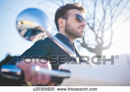 Low angle view of young man on moped View Large Photo Image Stock Image - Low angle view of young man on moped. Fotosearch
