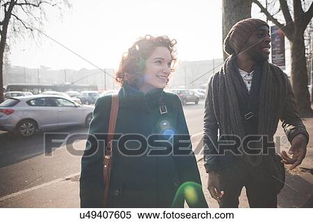 Stock Photography - Male and female adult friends strolling in city street. Fotosearch