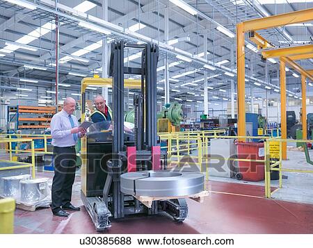 Manager and fork lift driver in engineering factory View Large Photo Image Stock Photo - Manager and fork lift driver in engineering factory. Fotosearch