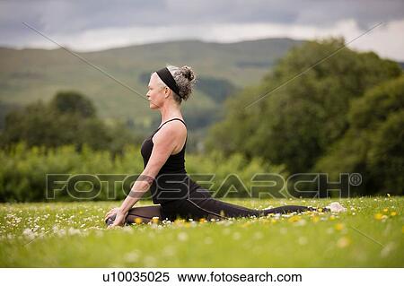 Mature woman doing splits practicing yoga position in field View Large Photo Image Stock Photography - Mature woman doing splits practicing yoga position in field. Fotosearch