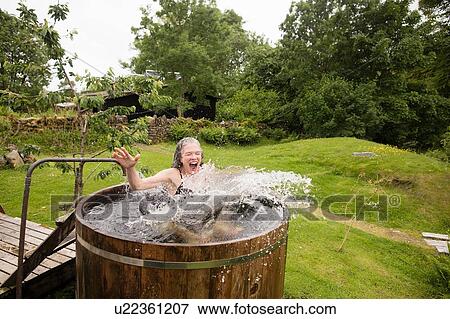 Mature woman jumping into fresh cold water tub at eco retreat View Large Photo Image Stock Photo - Mature woman jumping into fresh cold water tub at eco retreat. Fotosearch