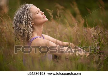 Mature woman meditating in long grass View Large Photo Image Stock Image - Mature woman meditating in long grass. Fotosearch