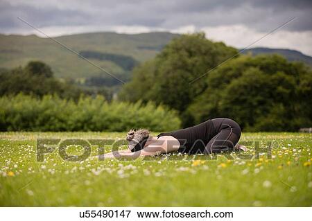 Mature woman practicing yoga childs position in field View Large Photo Image Stock Photo - Mature woman practicing yoga childs position in field. Fotosearch