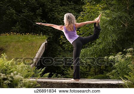 Mature woman practicing yoga dancer pose in garden View Large Photo Image Picture - Mature woman practicing yoga dancer pose in garden. Fotosearch