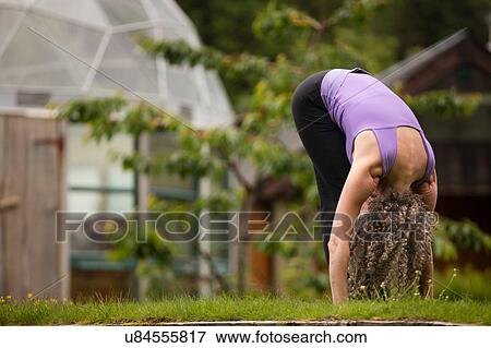 Mature woman practicing yoga forward fold in eco lodge garden View Large Photo Image Stock Photo - Mature woman practicing yoga forward fold in eco lodge garden. Fotosearch