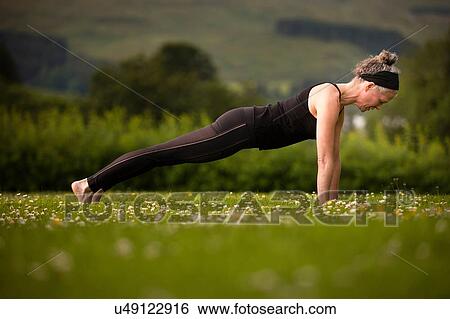 Mature woman practicing yoga plank in field View Large Photo Image Stock Photograph - Mature woman practicing yoga plank in field. Fotosearch