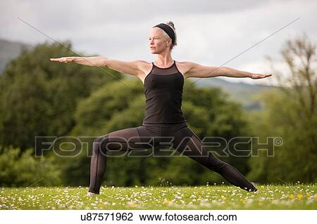 Mature woman practicing yoga reversed warrior pose with arms open in field View Large Photo Image Stock Image - Mature woman practicing yoga reversed warrior pose with arms open in field. Fotosearch