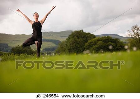 Mature woman practicing yoga tree pose in field View Large Photo Image Picture - Mature woman practicing yoga tree pose in field. Fotosearch
