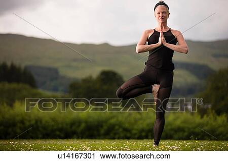 Mature woman practicing yoga tree position in field View Large Photo Image Stock Image - Mature woman practicing yoga tree position in field. Fotosearch