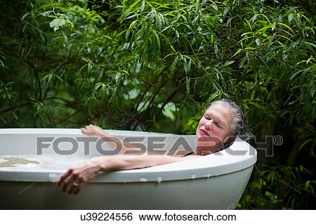 Mature woman relaxing in garden bubble bath at eco retreat View Large Photo Image Stock Photograph - Mature woman relaxing in garden bubble bath at eco retreat. Fotosearch