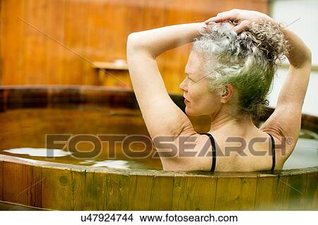 Mature woman with hands in hair in hot tub at eco retreat View Large Photo Image Picture - Mature woman with hands in hair in hot tub at eco retreat. Fotosearch