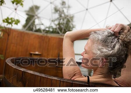 Mature woman with hands in hair in hot tub at eco retreat View Large Photo Image Stock Image - Mature woman with hands in hair in hot tub at eco retreat. Fotosearch