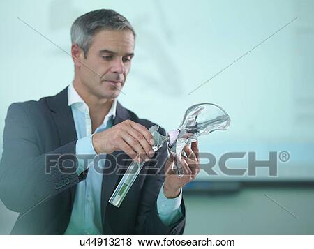 Stock Photo - Medical product designer inspecting hip joint model. Fotosearch