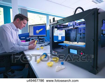 Stock Photograph - Medical product designer with 3D printing machine with CAD design on screen in orthopaedic factory. Fotosearch