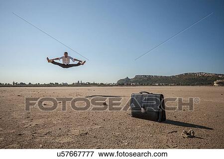 Mid adult businessman jumping mid air at beach View Large Photo Image Stock Photo - Mid adult businessman jumping mid air at beach. Fotosearch