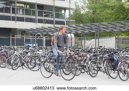 Mid adult man cycling past bike shed full of bicycles, looking away View Large Photo Image Stock Image - Mid adult man cycling past bike shed full of bicycles, looking away. Fotosearch